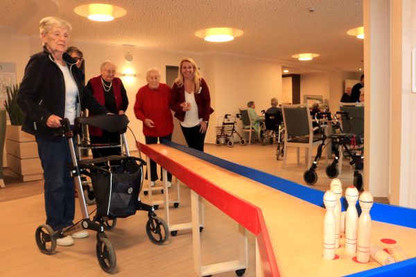 Mitarbeiter der Betreuung und Bewohner beim Kegeln im gemeinschaftlichen Wohnbereich